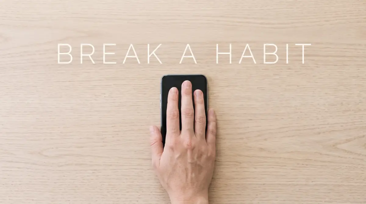 a hand setting a phone face-down on a table, a deliberate small choice